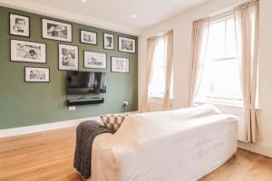 ein Wohnzimmer mit Sofa und Bildern an der Wand in der Unterkunft Modern & spacious 1 bedroom Clapham Junction flat in London