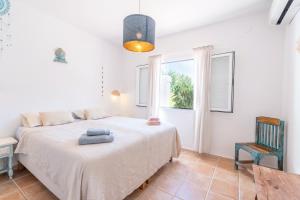 a bedroom with a bed and a chair and a window at Sunset SPA Villa Cala Tarida in Sant Josep de sa Talaia