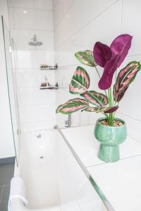 une fleur violette dans un vase vert sur un comptoir de salle de bains dans l'établissement Modern & spacious 1 bedroom Clapham Junction flat, à Londres