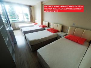 a room with four beds with red pillows on them at !FEMALES ONLY! Bakırköy Elit Kiz Yurdu in Istanbul