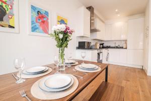 a kitchen with a wooden table with plates and flowers on it at Modern & spacious 1 bedroom Clapham Junction flat in London