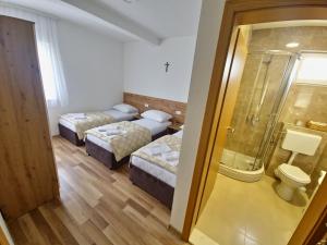 a hotel room with two beds and a shower at Pansion Vesna&Vlado Ostojic in Međugorje
