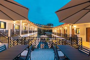 una terraza al aire libre con mesas, sillas y luces en The Chu’s Boutique Hotel, en Khao Lak