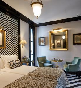 a bedroom with a bed and two chairs and a mirror at Triana House in Seville