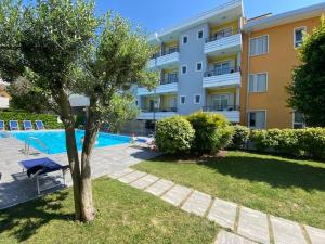 a large apartment building with a swimming pool and a tree at Residenza Viel in Bibione