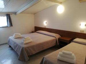 two beds in a hotel room with towels on them at Hotel La Bella Vita in Rimini