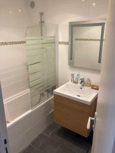 een badkamer met een wastafel, een bad en een spiegel bij TOP central Cabourg double terrasse 80m2 MER in Cabourg
