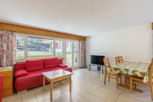 a living room with a red couch and a table at Haus Alfa in Saas-Fee