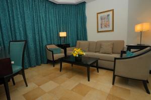 a living room with a couch and a table with flowers at Corp Amman Hotel in Amman