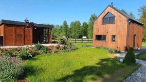 a wooden barn with a yard and a house at Zielone Wrzosowisko in Świętajno