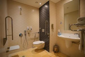 a bathroom with a shower and a toilet and a sink at Corp Amman Hotel in Amman
