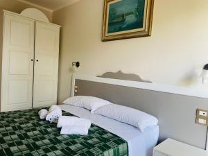 1 dormitorio con 1 cama con 2 toallas en Tanit Hotel Villaggio Ristorante en Carbonia