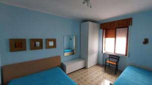 1 dormitorio azul con 2 camas y ventana en Appartamento vicino al mare a Scalea, en Scalea