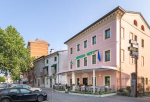 ein schwarzes Auto, das vor einem rosa Gebäude parkt in der Unterkunft Hotel City Verona in San Giovanni Lupatoto