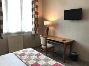 um quarto de hotel com uma secretária, uma cama e uma televisão em Logis La Villa des Houx em Aumale