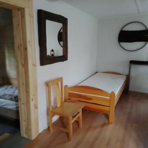 1 dormitorio con cama, silla y espejo en Warmia Odludzie, en Dębiny