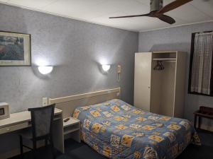 ミヨーにあるHotel des Voyageursのベッド、デスク、デスクが備わる客室です。