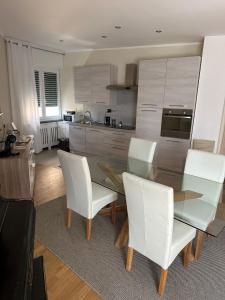 uma cozinha com uma mesa de vidro e cadeiras brancas em Luxury center appartment em Novi Ligure
