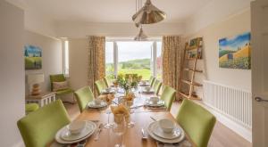 een eetkamer met een lange tafel en groene stoelen bij Hazelseat House in Sawrey