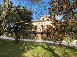 NOUVEAU Villa Olga في Jaujac: مبنى حجري قديم امامه اشجار