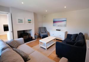 uma sala de estar com um sofá e uma cadeira em Newly renovated cottage with hot tub em Portreath