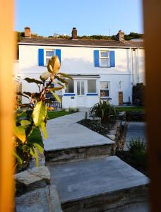 uma casa branca com persianas azuis em Newly renovated cottage with hot tub em Portreath