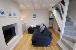 uma sala de estar com um sofá e uma televisão e escadas em Newly renovated cottage with hot tub em Portreath