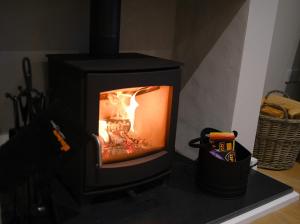 um fogão preto com um fogo dentro dele em Newly renovated cottage with hot tub em Portreath
