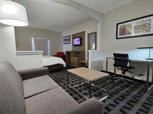 a hotel room with a couch and a desk and a bed at Quality Inn & Suites Irving DFW Airport South in Irving