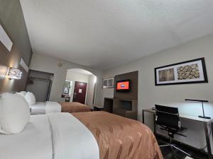a hotel room with two beds and a desk at Quality Inn & Suites Irving DFW Airport South in Irving