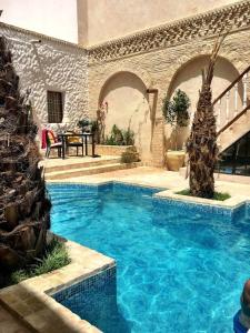 a large swimming pool in a house with a patio at Riad Dar El Caid - Palais XIII Siecle in Tozeur