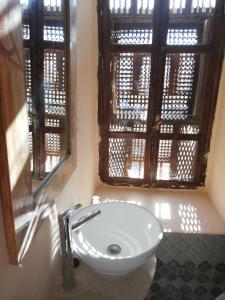 a white sink in a bathroom with a window at Riad Dar El Caid - Palais XIII Siecle in Tozeur