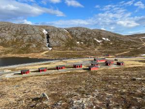 grupa czerwonych budynków w środku góry w obiekcie Hytte Camp Nordkapp - Red w mieście Skarsvåg