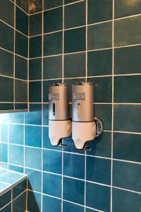 a couple of cups hanging on a blue tiled wall at La Porte des Prés in Cluny