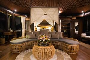 - un salon avec un canapé et une table fleurie dans l'établissement Green Tree House Villa Ubud, à Ubud