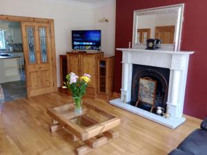 a living room with a fireplace and a vase of flowers at Tullynacrunat Lodge in Castleblayney