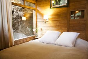 1 cama con 2 almohadas en una habitación con ventana en Tree House Lodge, en Machu Picchu