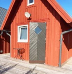 une grange rouge avec une porte et un tabouret devant dans l'établissement Boat house with direct connection to the sea, à Umeå