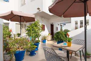 patio con piante in vaso e tavolo con ombrellone di Angelica's Deluxe Rooms in Adamas ad Adámas