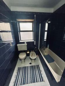 y baño azul con aseo y bañera. en Duplex em casa inteiro. 4 quartos. Bem localizada., en Bragança