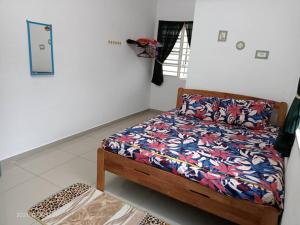 - une chambre avec un lit et une couette colorée dans l'établissement Dina Homestay B, à Pasir Puteh