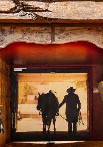 a man walking a horse through a door at Hotel Le Ranch in Brûlon