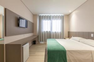 1 dormitorio con 1 cama y TV en la pared en Tri Hotel Executive Osório, en Osório