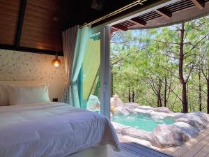 a bedroom with a bed and a view of a pool at Villa PaSon in Khao Kho