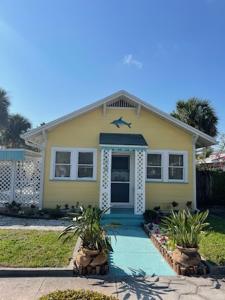 a yellow house with a blue door and a porch at Seahorse Bungalow in St. Pete Beach