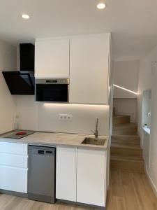 a kitchen with white cabinets and a sink and a staircase at Casa Moralzarzal jardin Sierra Madrid in Moralzarzal