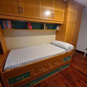 uma cama num quarto com armários de madeira em piso en noia em Noya