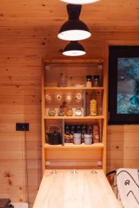 a room with wooden walls and a shelf with food at Tiny Heaven Cabin in Călimăneşti