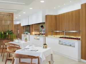 a restaurant with white tables and chairs and a counter at XQ El Palacete in Morro del Jable