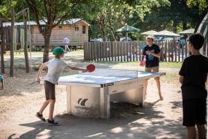 a group of boys playing ping pong on a table at Huttopia Les Châteaux in Bracieux